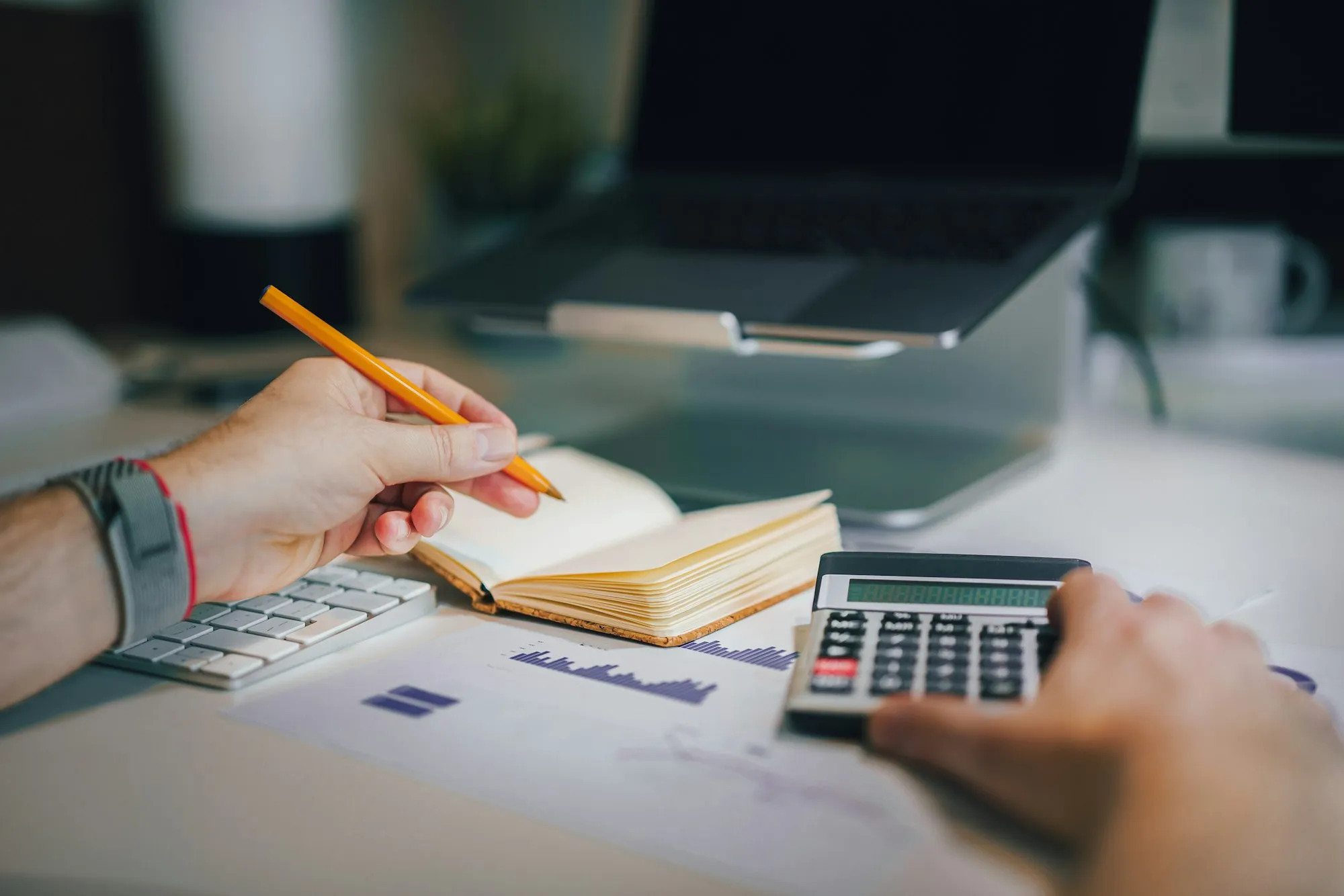 Des mains vérifient des chiffres avec une calculatrice et un carnet