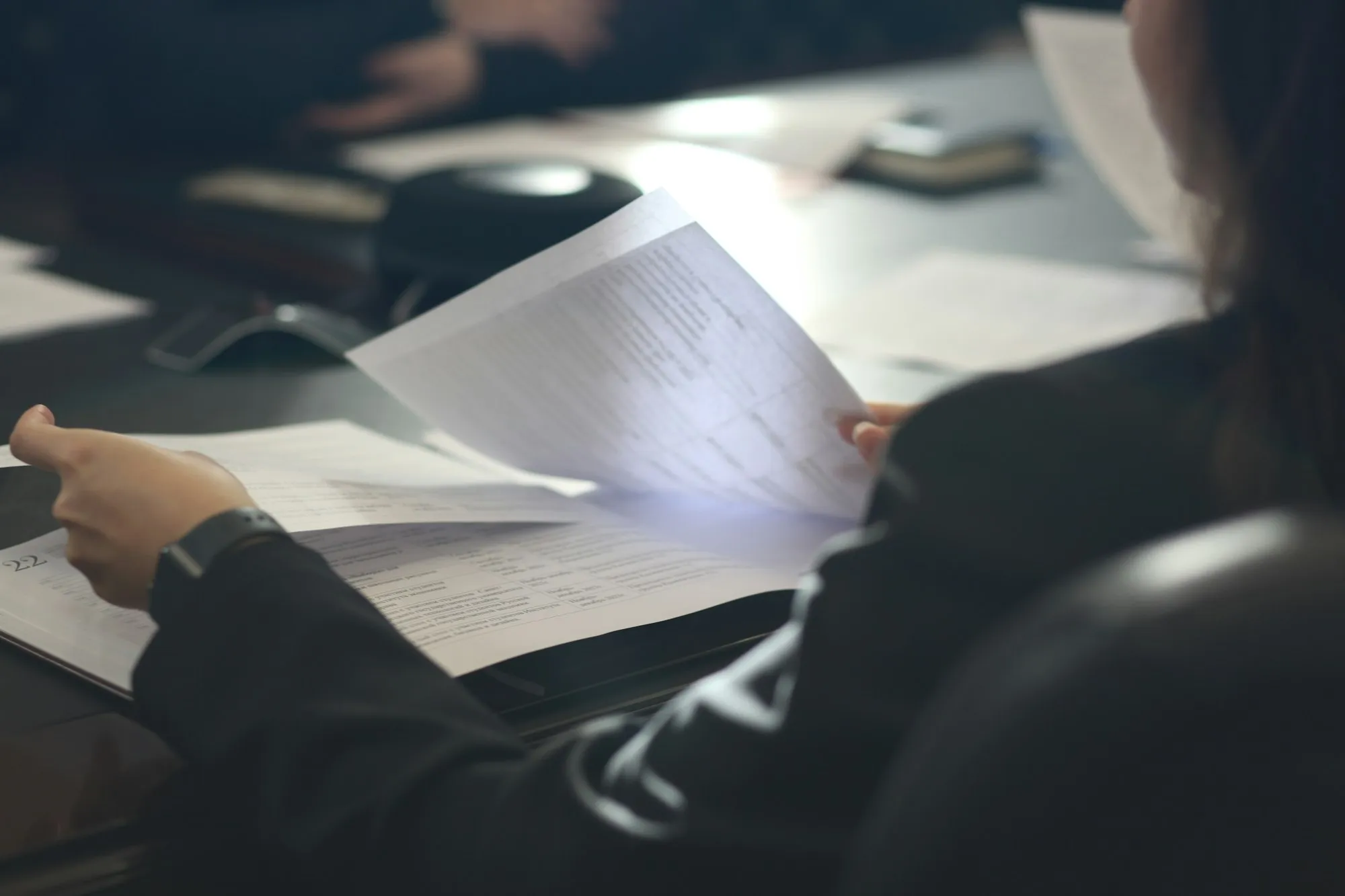 A person reading a printed document at a meeting table