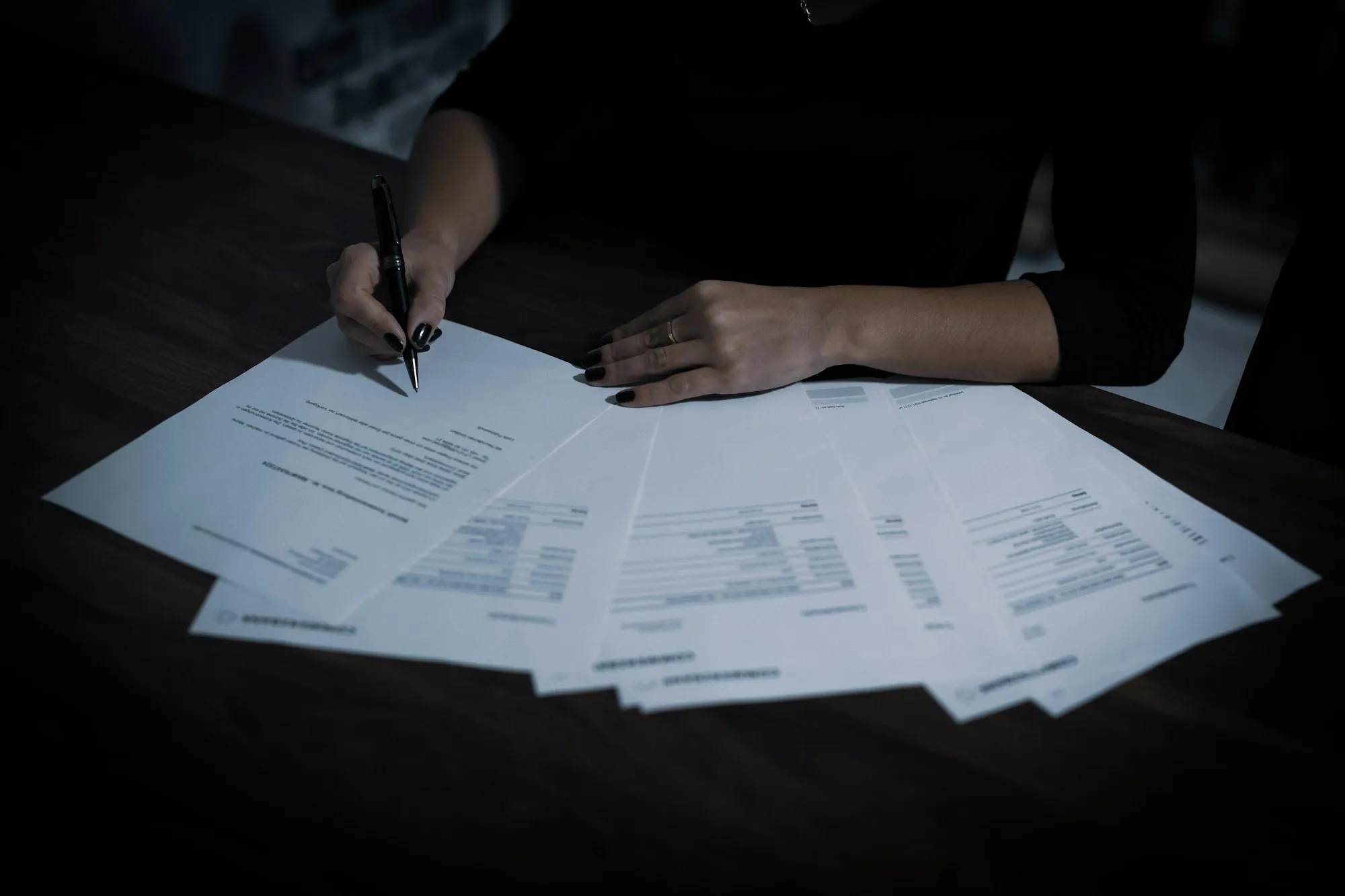 A lawyer marks up the pages of a contract spread across her desk