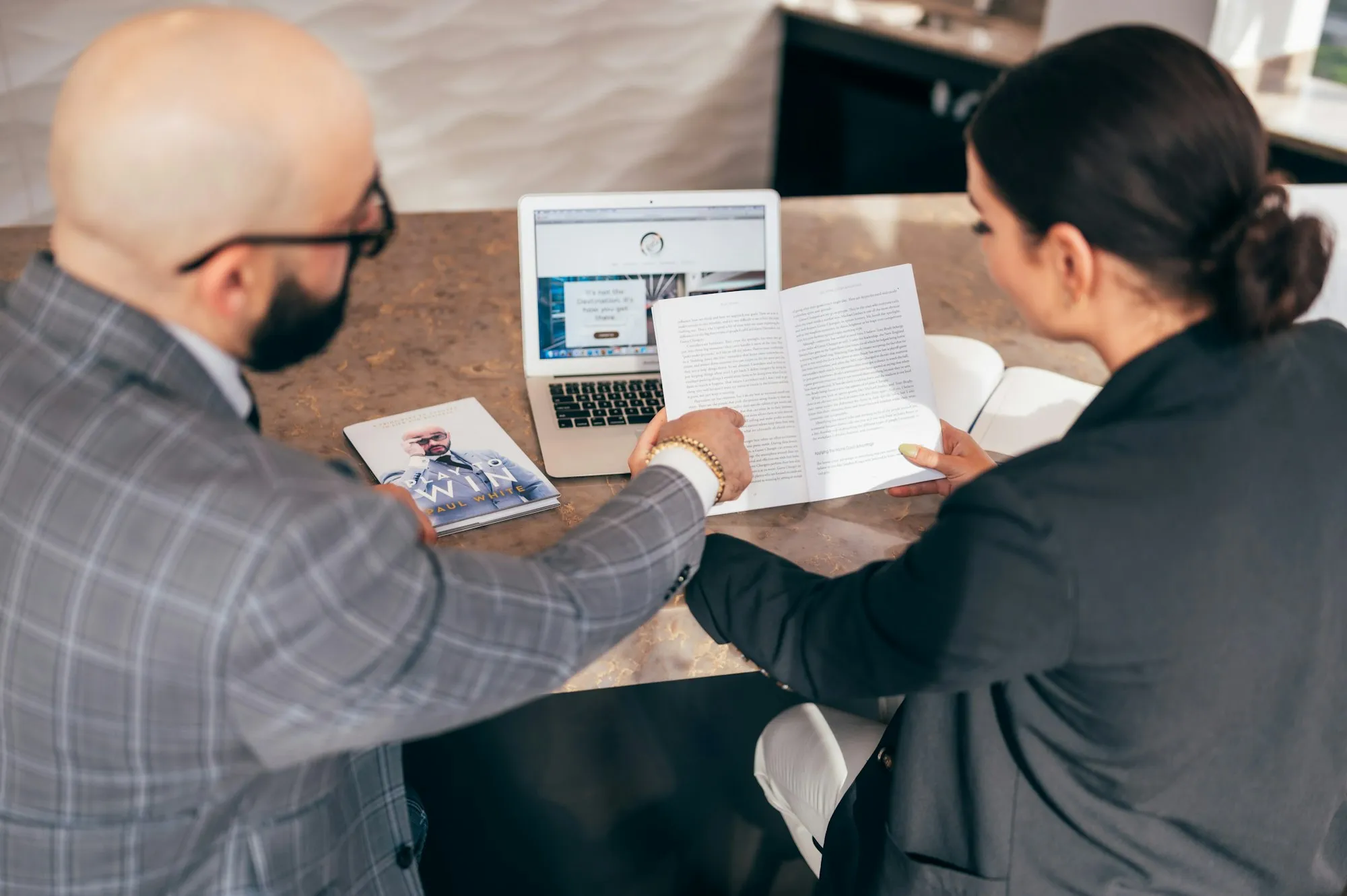 An advisor goes through a printed file with a client at his desk