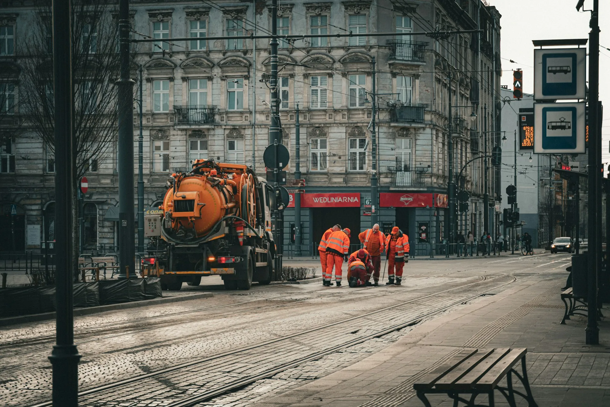 City maintenance workers in orange uniforms at work on a street with tram tracks