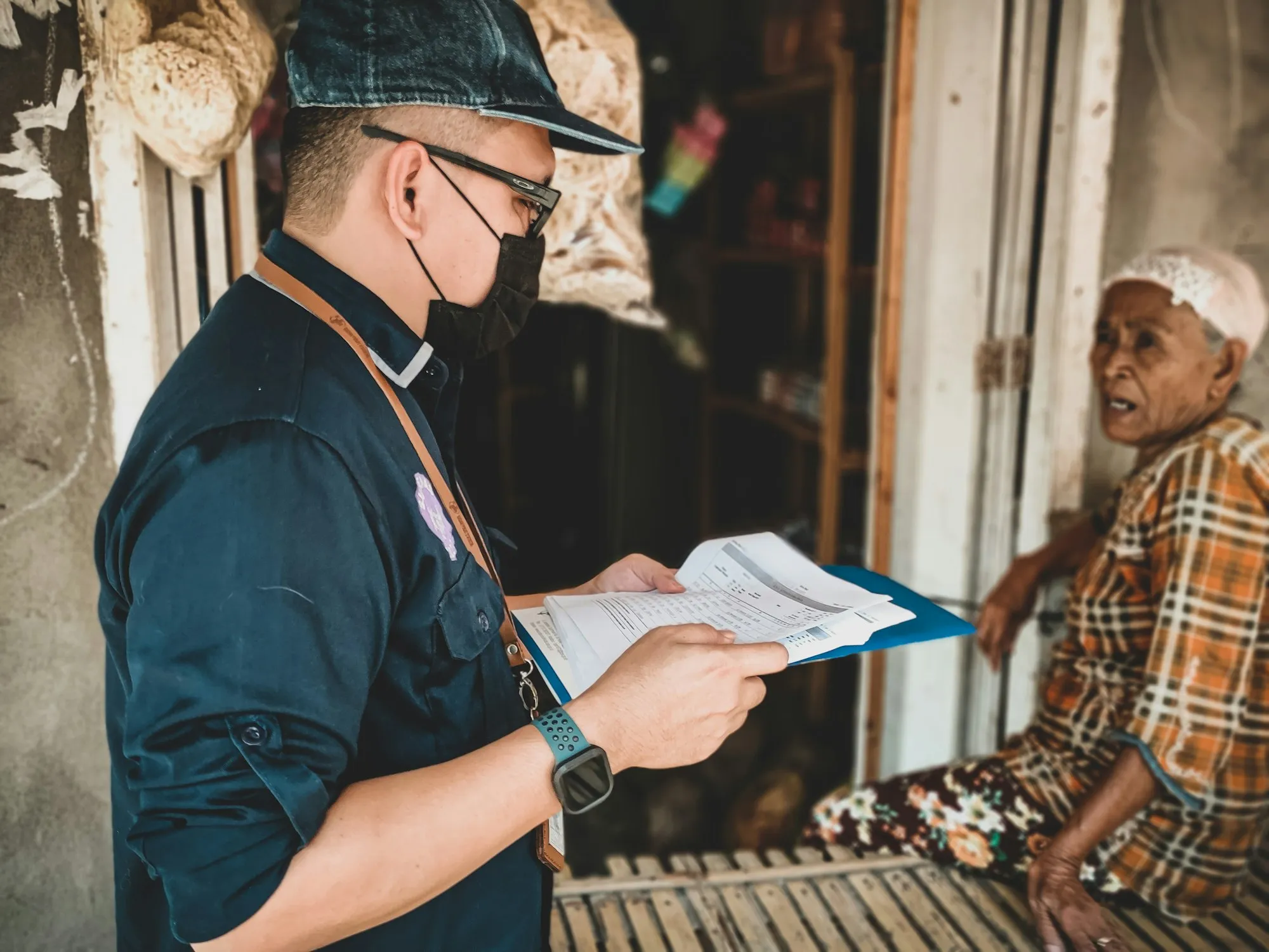A man with a clipboard taking notes with a resident at her door