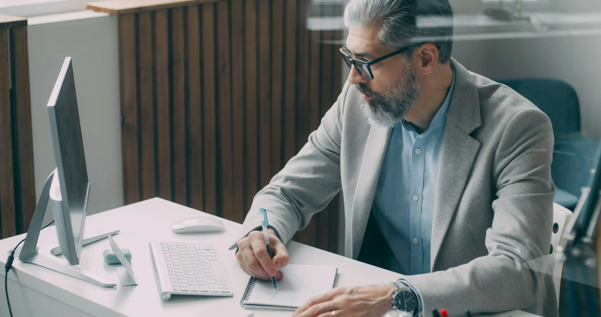 A man in a suit annotating a document at his desk