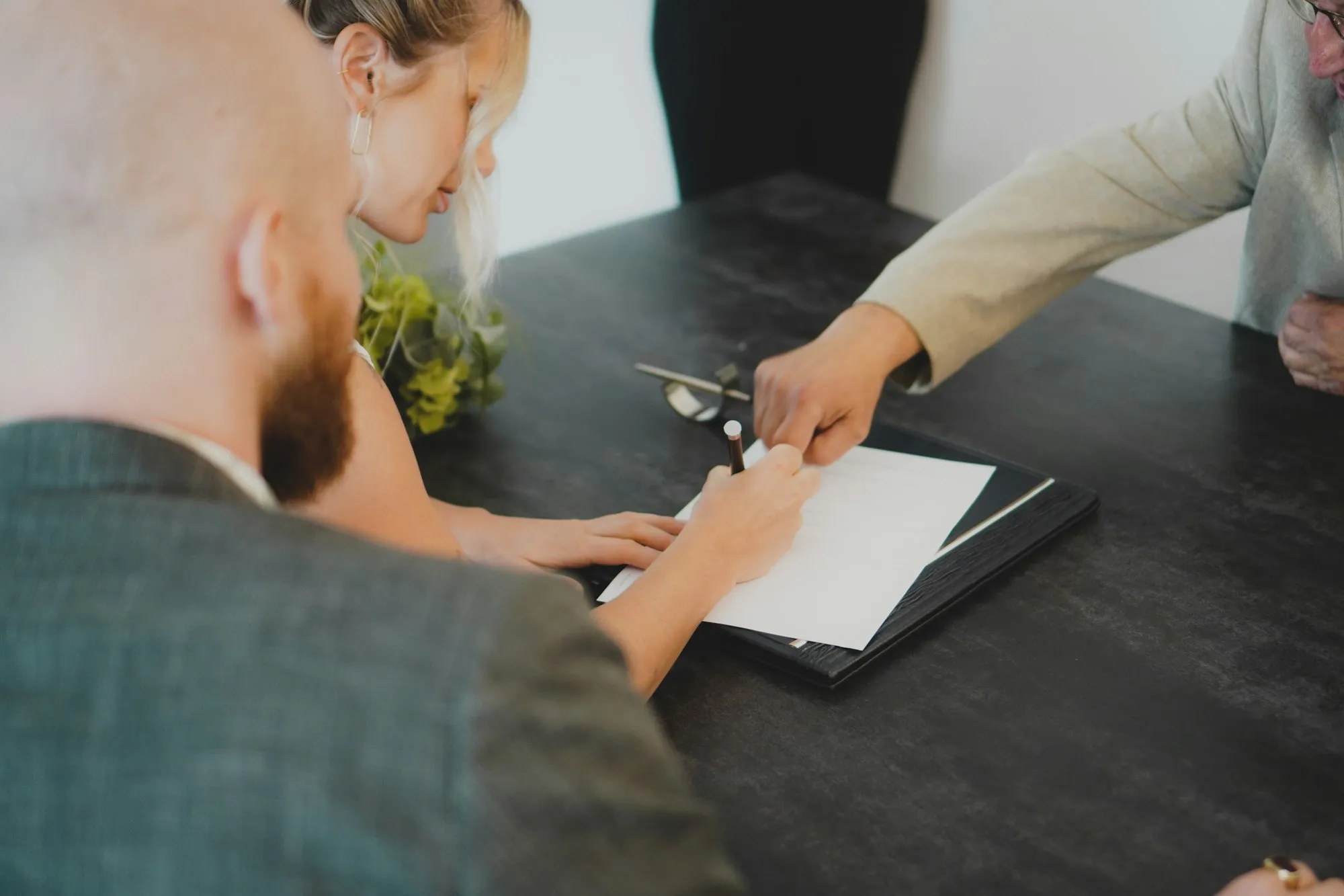Un couple signe un document face à un professionnel, à son bureau